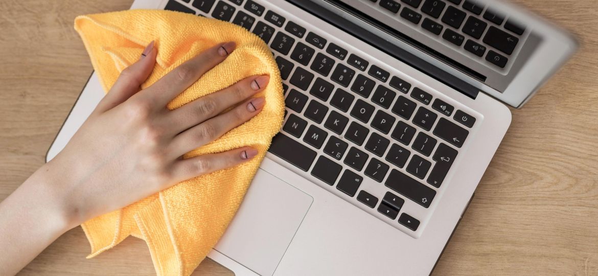 top-view-woman-cleaning-laptop-with-cloth